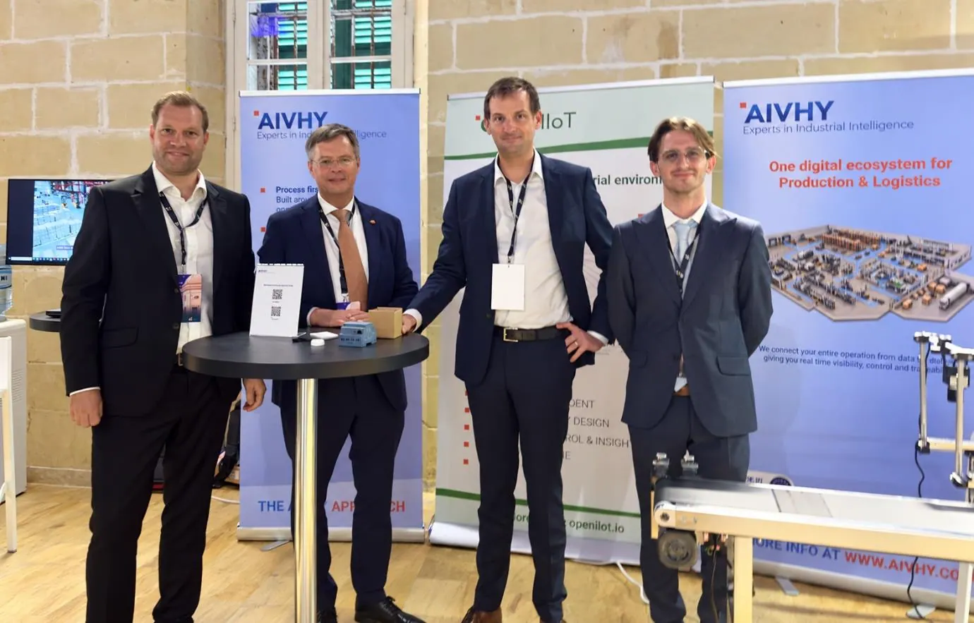 Vier vertegenwoordigers bij de stand van AIVHY en OpenIIoT tijdens de BAS-lancering op EY Malta’s Future Realised-evenement.